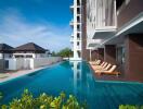 Luxurious building exterior with large swimming pool and sun loungers