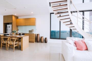 Modern open-plan living area with kitchen, dining, and lounge space, featuring staircase