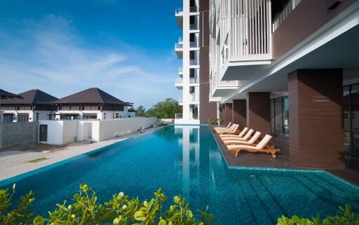 Luxurious poolside with loungers adjacent to a modern apartment building