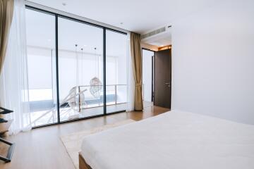 Spacious and modern bedroom with large glass doors leading to a balcony