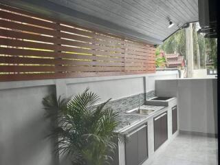 Modern outdoor kitchen with wooden accents and stainless steel appliances