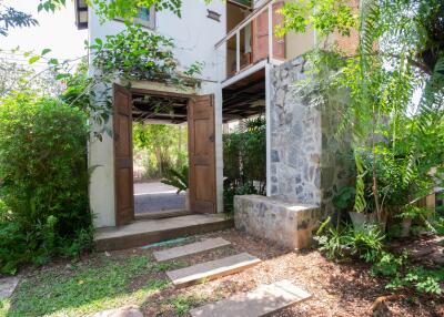 Exterior view of a residential building with a welcoming entrance surrounded by lush greenery