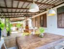 Spacious covered patio with rustic wooden dining table and ambient lighting