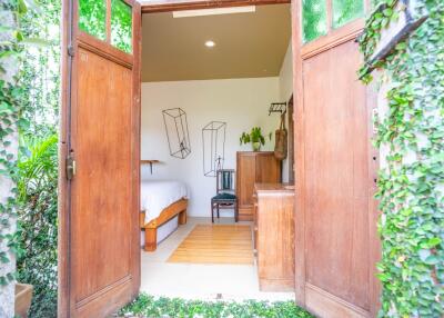 Airy bedroom with open wooden doors leading to a lush garden