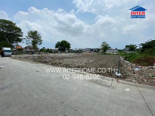 View of an undeveloped building site with visible debris and surrounding infrastructure