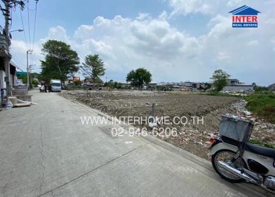 Vacant land ready for development next to a paved road with clear skies