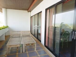 Spacious balcony with ocean view, wooden bench, and sliding glass doors