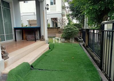 Elegant outdoor patio with lush green artificial turf and covered seating area by a modern home