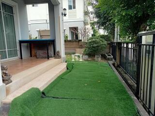 Elegant outdoor patio with lush green artificial turf and covered seating area by a modern home