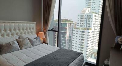 Elegant bedroom with a large window providing a cityscape view