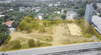 Aerial view of a spacious vacant land plot highlighted in yellow for development