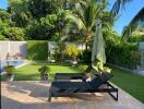 Outdoor garden with pool, sun loungers, lush green landscape, and privacy walls