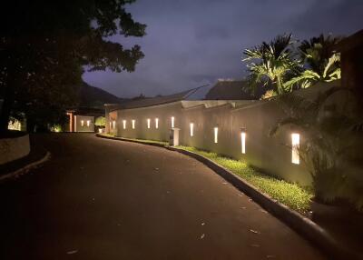 Night view of a residential area with illuminated pathway and surrounding greenery