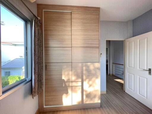 Bright bedroom with large wooden wardrobe and scenic window view
