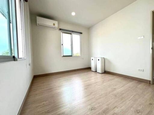 Spacious, empty bedroom with large window and air conditioning unit