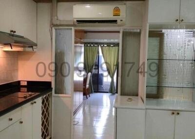 Compact kitchen leading into living area with modern appliances