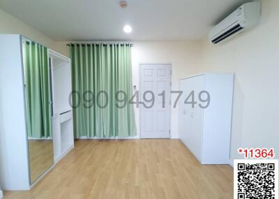 Spacious and well-lit bedroom with green curtains and air conditioner