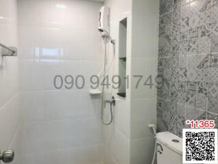 Modern white tiled bathroom with patterned wall and electric shower
