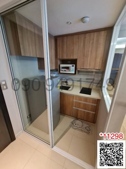 Modern compact kitchen with wooden cabinetry and built-in appliances viewed through a mirrored door