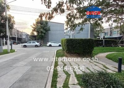 Well-maintained gated community entrance with lush greenery and paved road