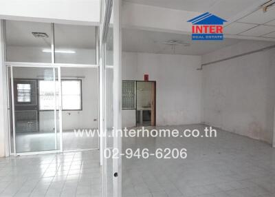 Spacious open-plan interior space with tiled floors, large windows, and visible staircase.