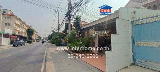 Exterior view of a residential building next to a street lined with utility poles and lush greenery