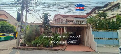 Exterior view of a residential house with a front garden and gated driveway