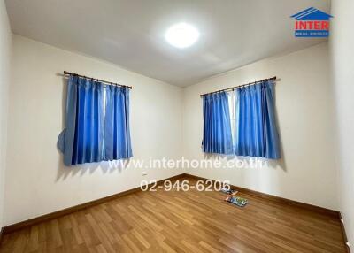 Spacious empty bedroom with blue curtains and wooden floor