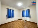 Spacious empty bedroom with blue curtains and wooden floor