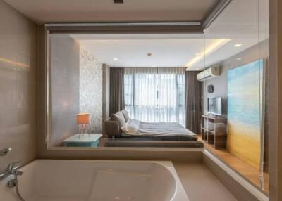 Modern bedroom with integrated bathroom design featuring a large bed, bathtub, and artistic decor
