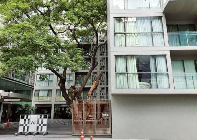 Modern apartment building facade with balconies and large tree in front