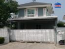 Modern single-family home with white exterior and gated entry