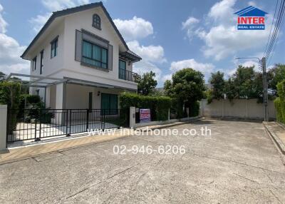 White detached house with driveway and real estate sign under clear sky
