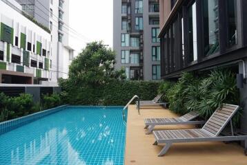 Swimming pool with lounging chairs and modern building in the background