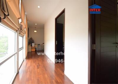 Spacious hallway leading to light-filled rooms, featuring wooden flooring and large windows
