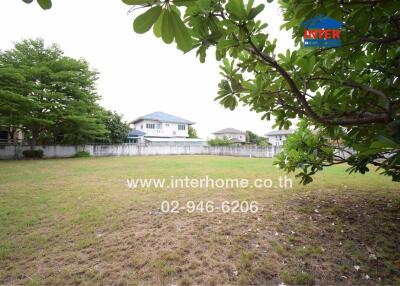 Spacious backyard of a residential property with a large grassy area and a view of a blue house