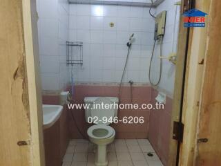 Compact bathroom with pink and white tiles and essential fixtures