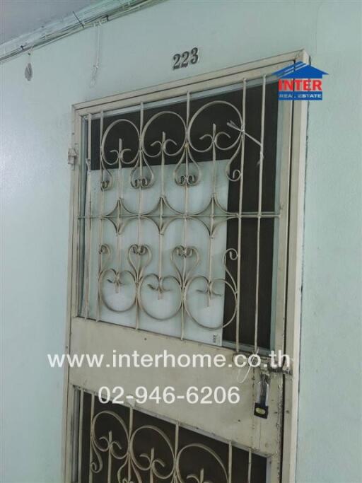 Secure entrance of a residential building unit with metal gate and door numbers