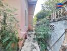 Side exterior view of a residential building with overgrown plants