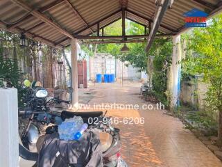 Spacious outdoor area with shelter including parked motorcycles and various storage items