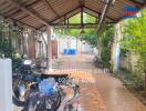 Spacious outdoor area with shelter including parked motorcycles and various storage items