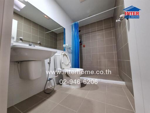 Modern bathroom interior with blue shower curtain and neutral tiles