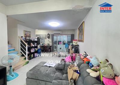 Spacious and cluttered living room with sectional sofa and various personal items