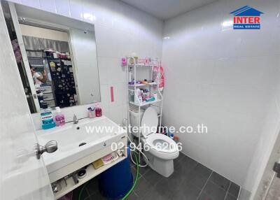 Modern white tiled bathroom with toilet and sink