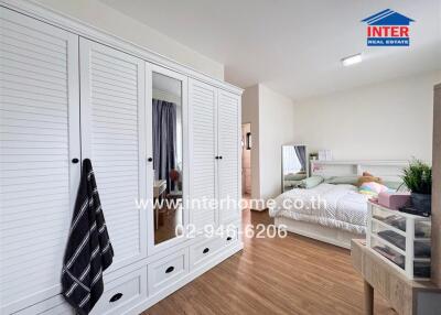 Spacious bedroom with large white closet and cozy bedding