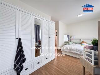 Spacious bedroom with large white closet and cozy bedding