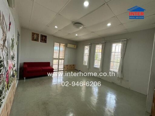 Spacious and well-lit living room with red sofa and multiple windows