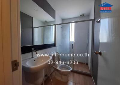 Modern bathroom interior with glass shower, white fixtures, and large mirror