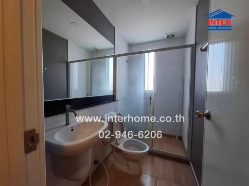 Modern bathroom interior with glass shower, white fixtures, and large mirror