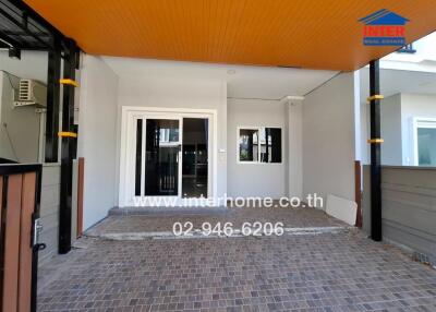 Covered patio area of a modern home with tiled flooring and bright orange ceiling